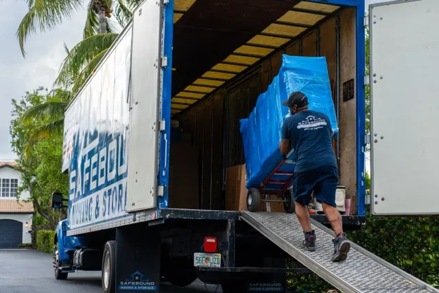 Safebound mover loading carefully wrapped household furniture into a branded moving truck